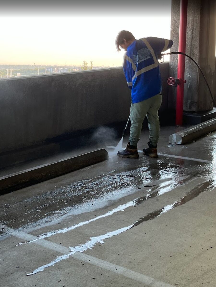Crew member wand-washing along a garage wall
