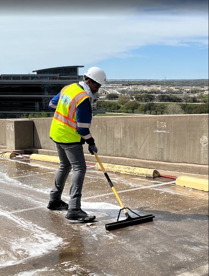 Crew member squeegeeing rinse water across a rooftop deck